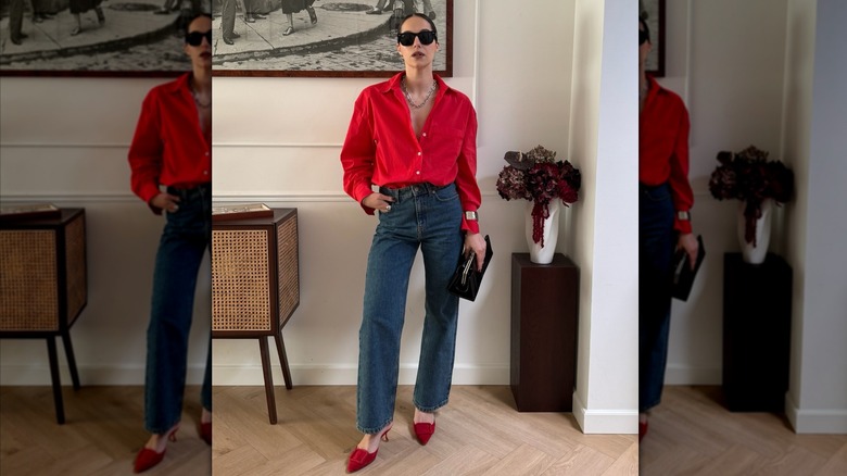 Une femme posant tout en portant une chemise rouge avec un jean bleu et des chaussures rouges