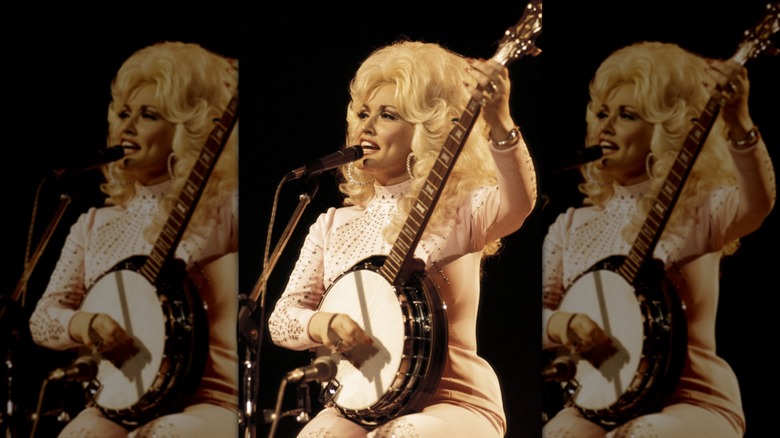 Dolly Parton joue du banjo sur scène dans un costume rose pâle assorti