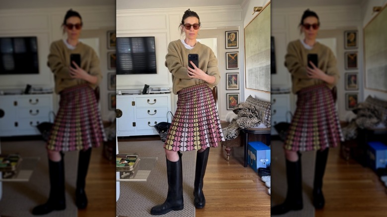 Une femme en bottes hautes, jupe et pull