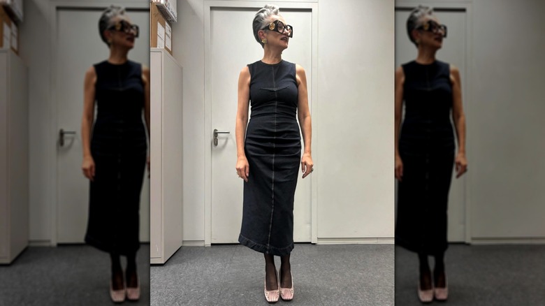 Une femme vêtue d'une robe noire avec des chaussures en satin rose et des lunettes tendance