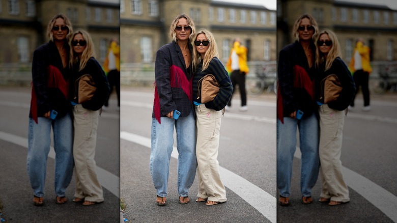 Deux femmes dans la rue portant des jeans amples et surdimensionnés, l'une bleu clair et l'autre blanche