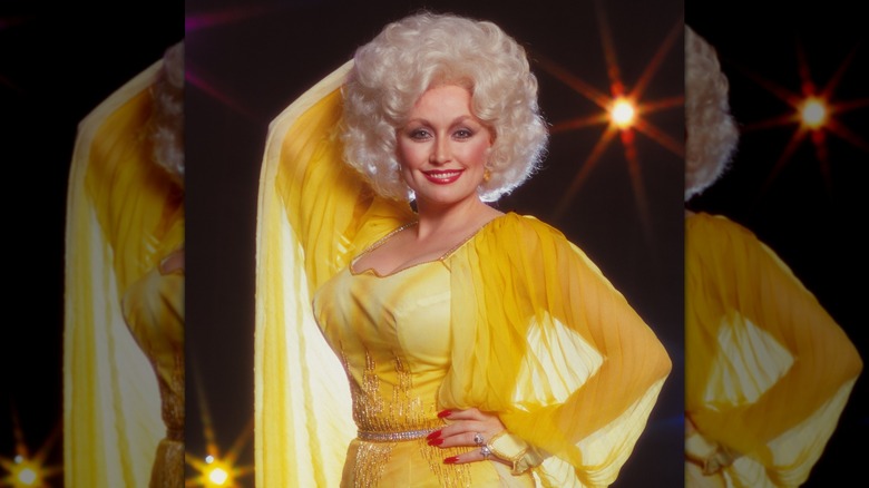 Dolly Parton en jaune avec des ongles rouges