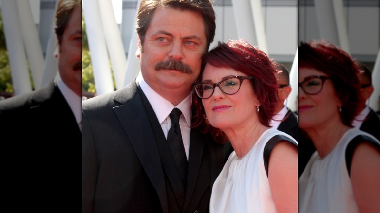 Megan Mullally portant une robe blanche avec des détails noirs et Nick Offerman dans un costume et une cravate noirs