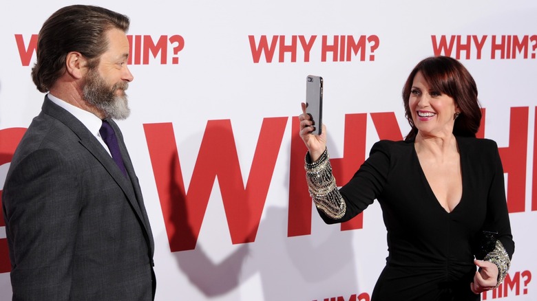 Megan Mullally portant un blazer noir et Nick Offerman portant un costume gris avec une cravate violette