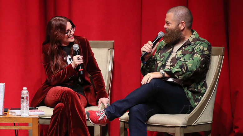Megan Mullally portant un costume en velours rouge et Nick Offerman en imprimé camouflage