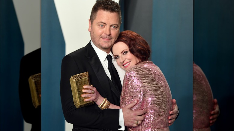 Megan Mullally portant une robe rose à paillettes et Nick Offerman dans un costume noir et une cravate