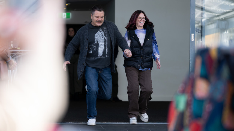 Megan Mullally porte une doudoune bleue et Nick Offerman un pull gris