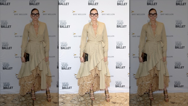 Jenna Lyons pose portant une robe style trench beige à volants et une jupe à pois