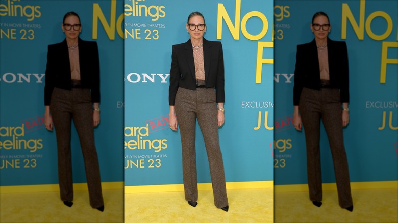 Jenna Lyons pose portant un haut en résille et un blazer court noir.