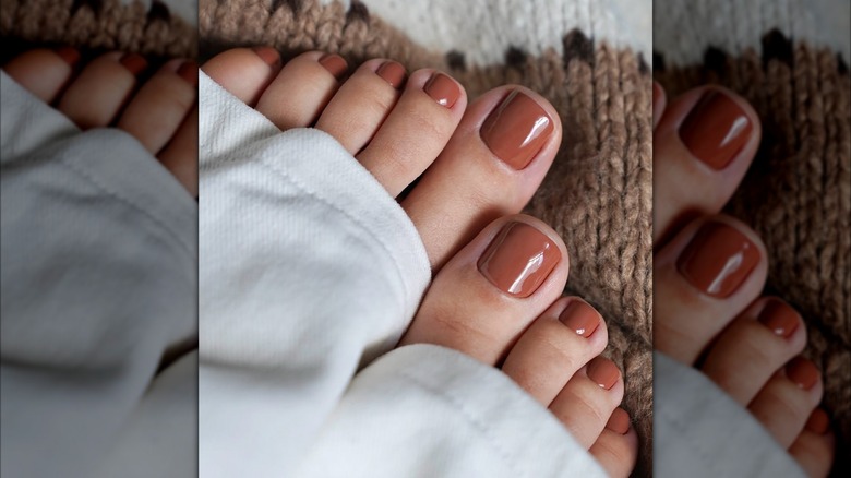 Pieds avec des ongles peints, sortant d'un pantalon blanc