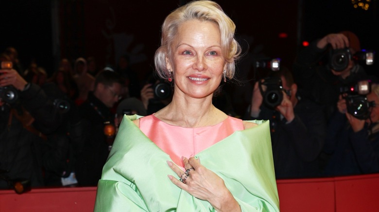 Pamela Anderson dans une robe rose et un châle vert lors d'un événement