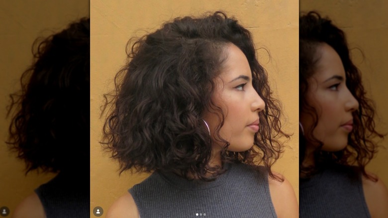 Profil latéral d'une femme aux cheveux bouclés coupés au carré jusqu'aux épaules.