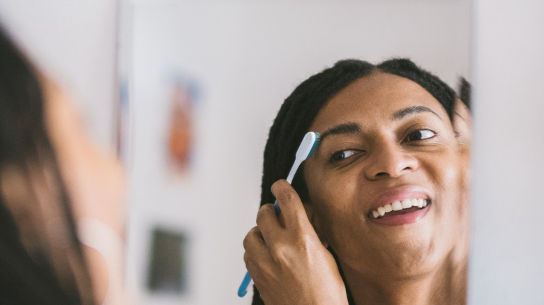 les femmes impatientes de se brosser les sourcils à la fin avec une brosse à dents