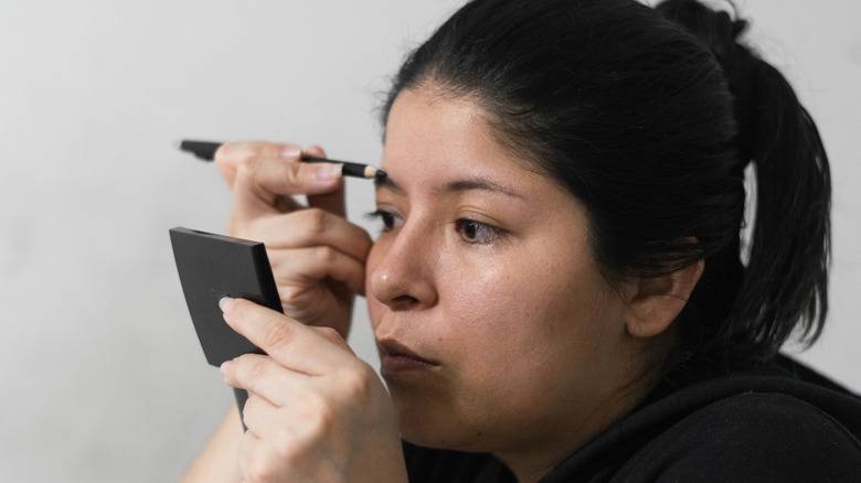 les femmes plus âgées regardent avec impatience dans un petit miroir portant une chemise noire