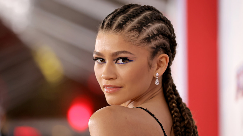 Zendaya sourit avec des tresses et un eye-liner bleu et blanc métallisé