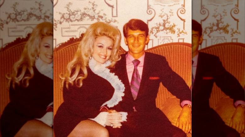 Instantané rétro de Dolly Parton assise avec son mari Carl Dean sur un canapé alors qu'ils sourient devant la caméra
