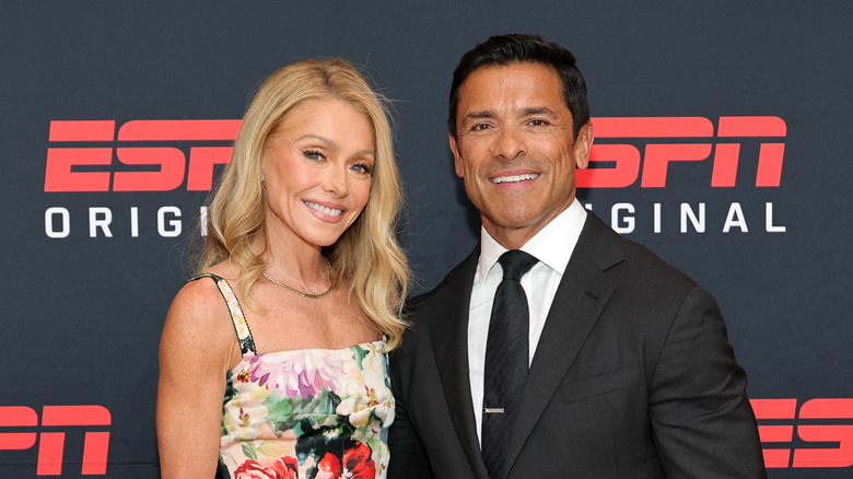 Kelly Ripa dans une robe à fleurs et Mark Consuelo portaient un costume noir