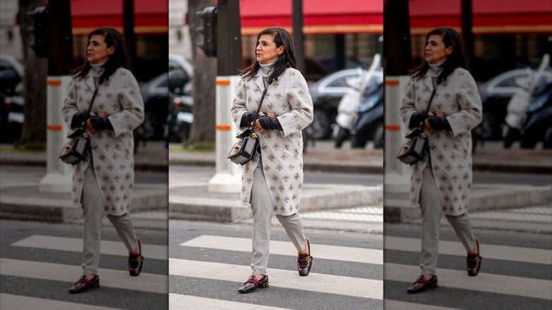 Une femme plus âgée marchant dans la rue portant principalement des vêtements neutres