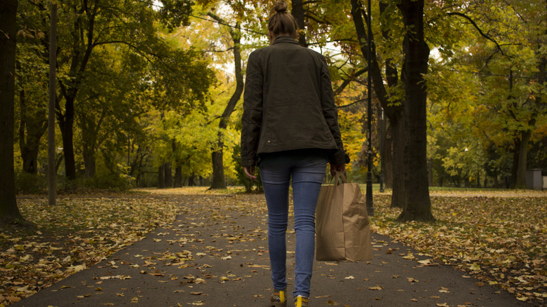 Une femme par derrière marchant dans un jean skinny et une veste verte