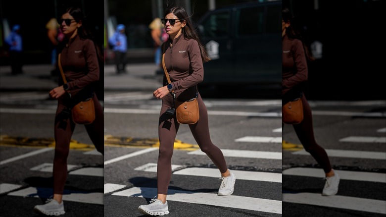 Une femme en leggings marron et baskets blanches traversant la rue