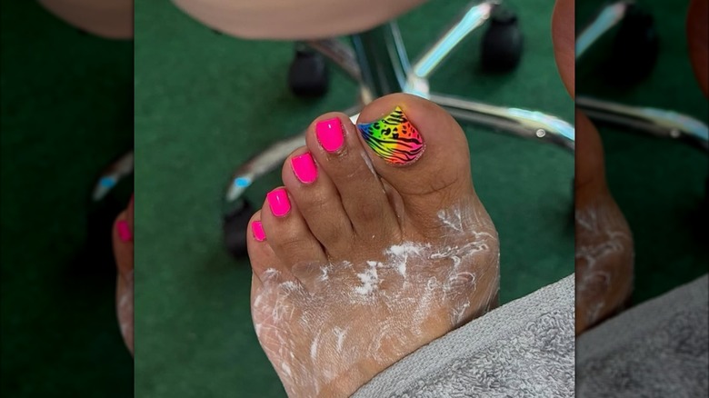 Gros plan d'une femme qui se fait faire une pédicure avec des ongles roses et brillants