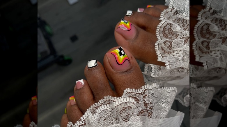 Une femme avec des détails en noir et blanc et des motifs colorés sur une pédicure