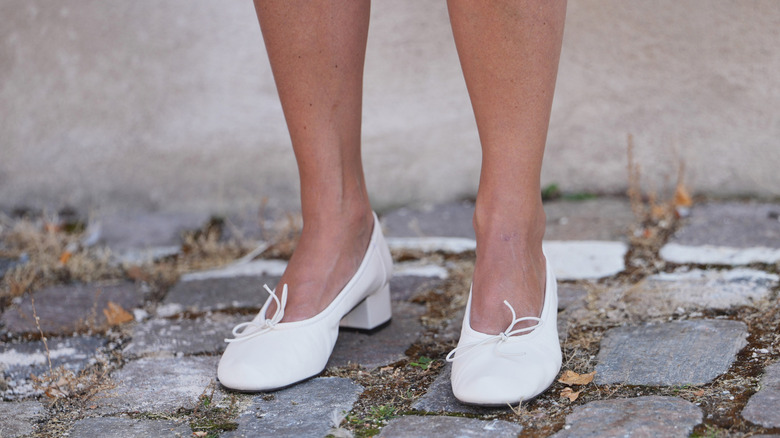 Femme portant des talons bas blancs avec de fins nœuds