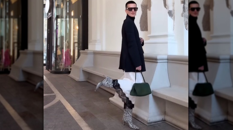 Une femme posant dans la rue dans une jupe blanche, un blazer et des bottes à imprimé zèbre