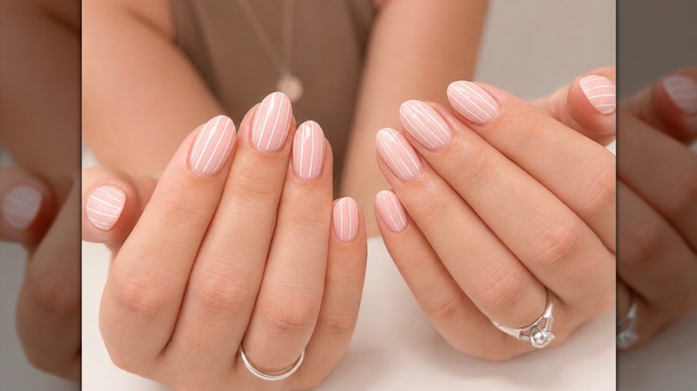 Ongles à fines rayures rose pâle avec une couleur d'accent blanche