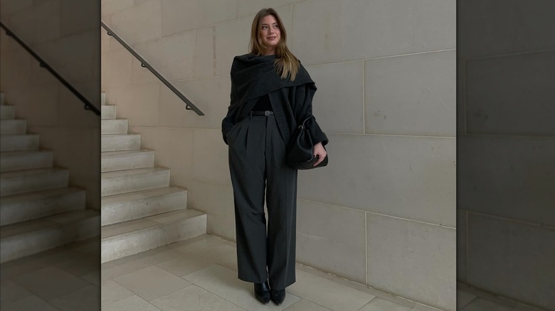 Une femme portant un cardigan foulard noir avec un pantalon noir