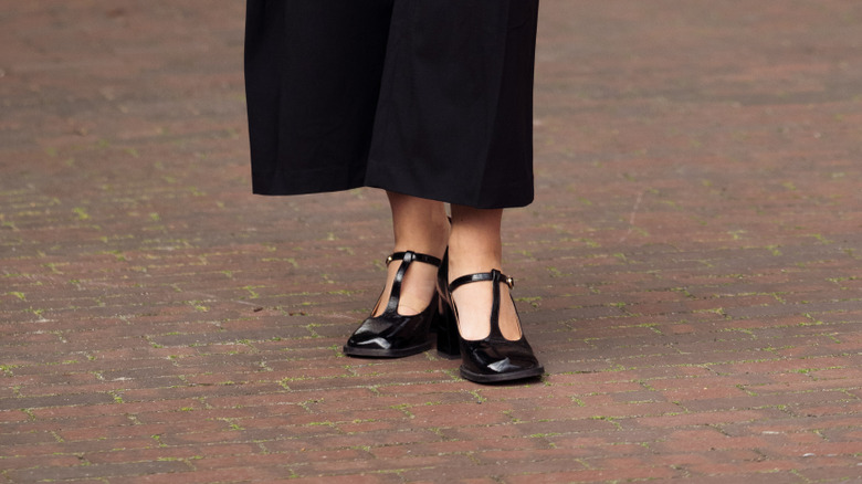 Une femme portant un pantalon noir et des chaussures noires à barre en T
