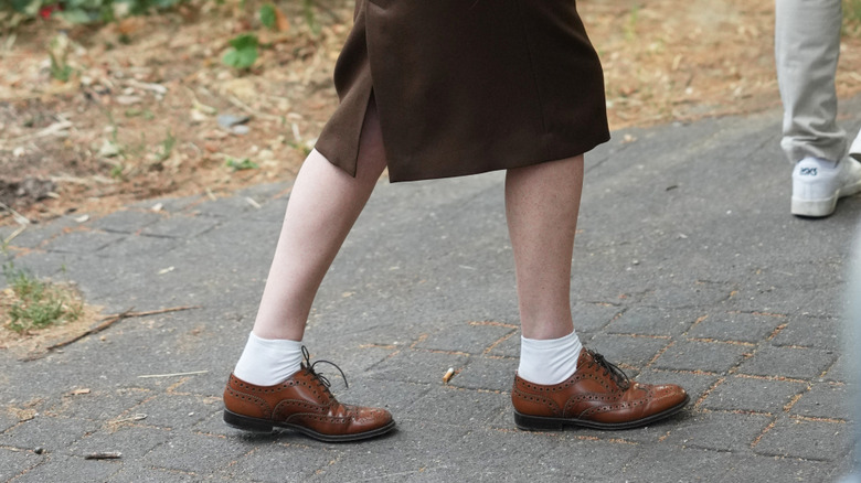Une femme portant une jupe crayon marron et des chaussures Oxford marron