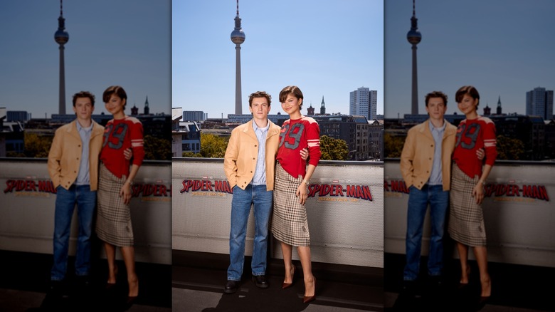 Zendaya portant une jupe à carreaux et des manches longues rouges sportives et Tom Holland portant un jean et une veste pêche
