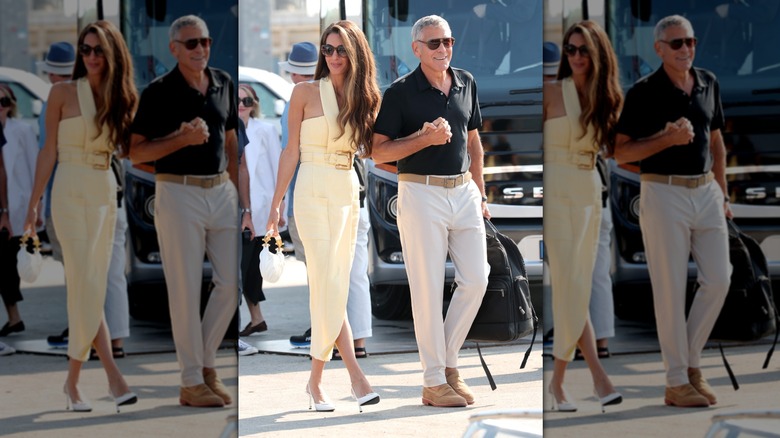 Amal Clooney portant une robe jaune et George Clooney portant un polo noir et un pantalon crème