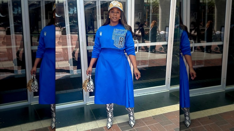 Une femme portant une casquette avec un sweat-shirt court et une jupe bleu cobalt