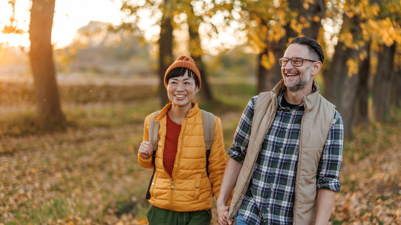 Heureux couple se tenant la main tout en profitant d'une promenade relaxante dans la nature d'automne