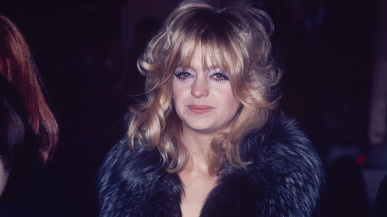 Goldie Hawn sourit dans un manteau noir bordé de fourrure