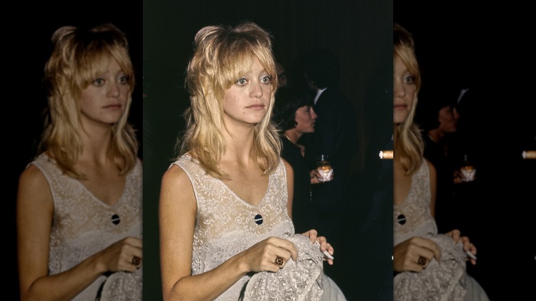 Goldie Hawn portant une robe blanche en dentelle avec des couches dans les cheveux