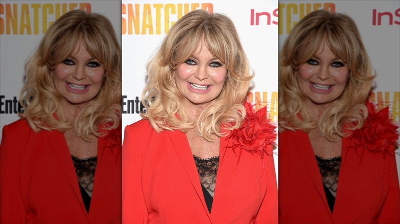 Goldie Hawn sourit en portant un blazer rouge