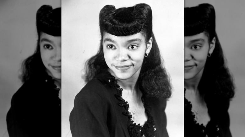 Photographie vintage d'une jeune femme des années 1940 portant des rouleaux de victoire dans les cheveux