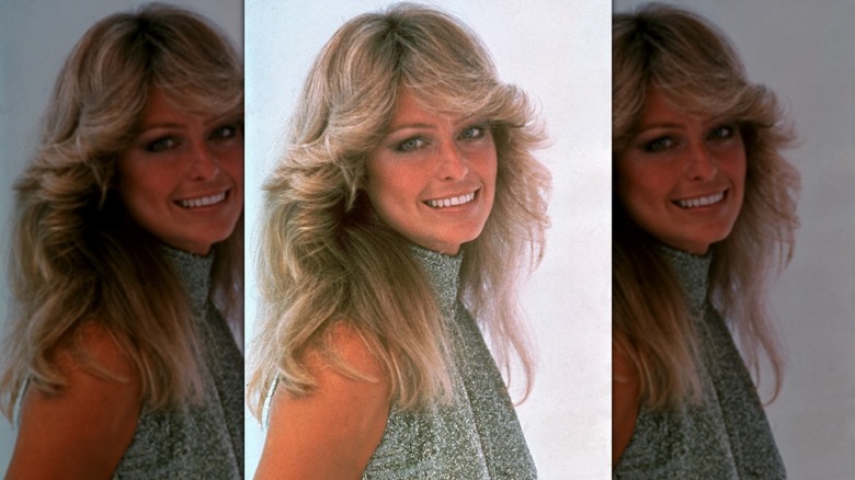 Farrah Fawcett regardant sur le côté et face à la caméra avec ses cheveux coiffés en couches de plumes et sa frange au milieu