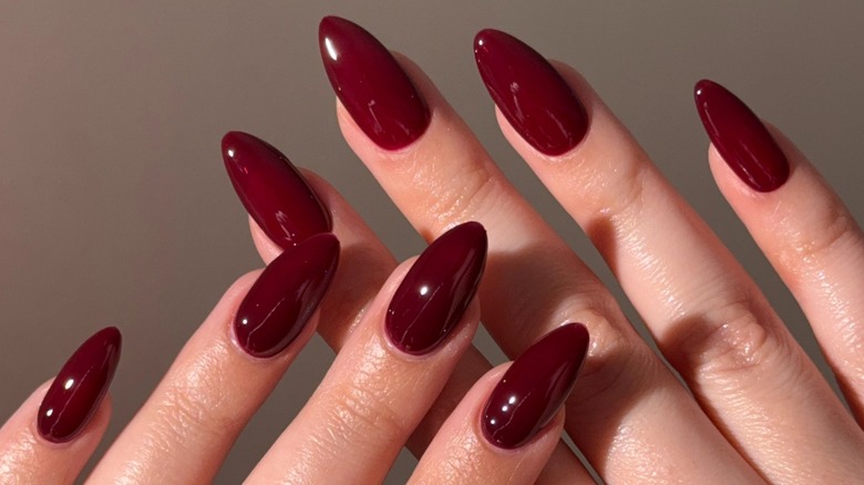Deux mains avec des ongles longs et une manucure rouge cerise