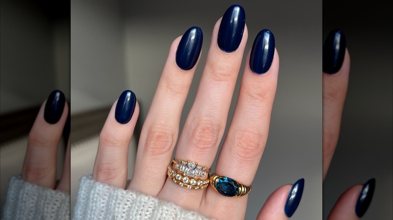 Une main au teint frais avec une manucure bleu marine foncé