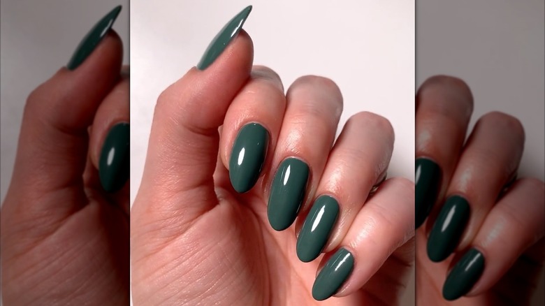 Une main aux tons froids portant un vernis à ongles vert aux tons froids