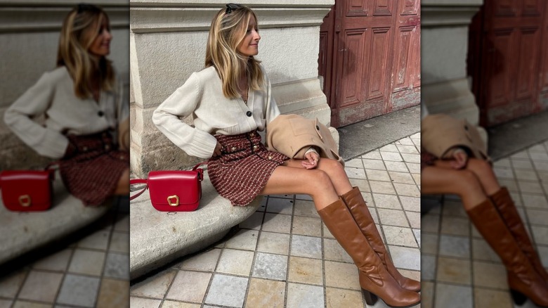 Une femme portant une jupe courte en tweed et des bottes marron à l'extérieur alors qu'elle est assise