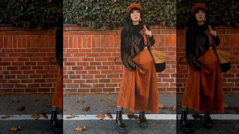 Une femme dans une jupe longue orange brûlé avec des bottes basses à l'extérieur