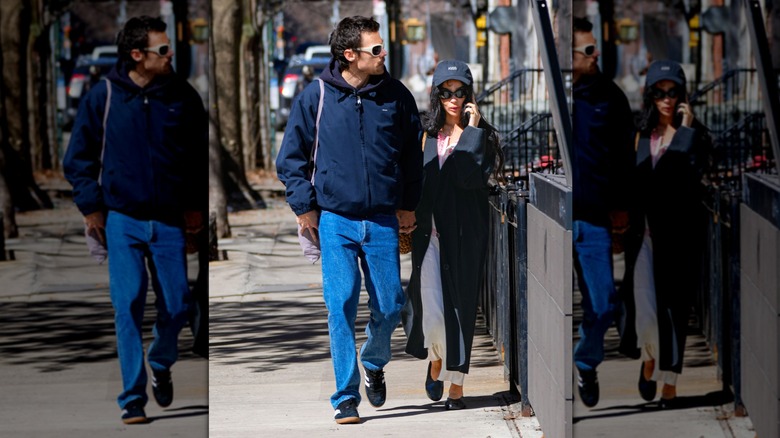 Zoë Kravitz porte des lunettes de soleil noires et une jupe blanche et Harry Styles marche avec un jean bleu et des lunettes de soleil blanches