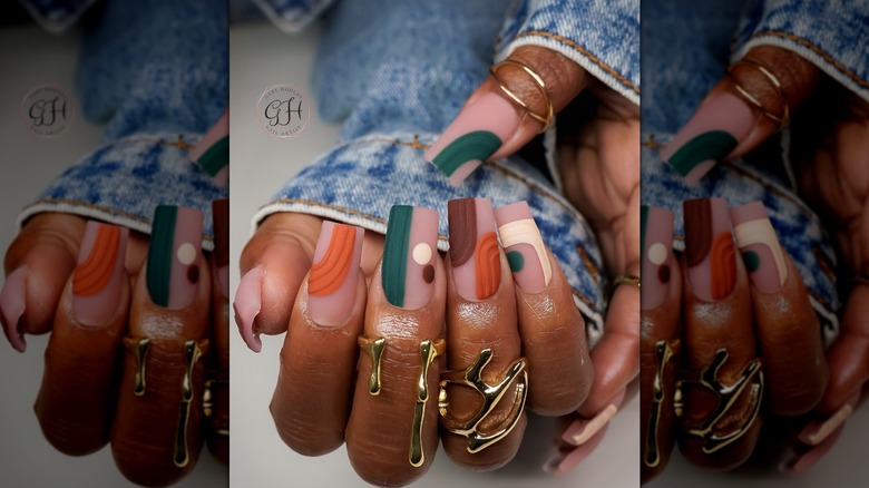 Deux mains montrant un dessin d'ongles abstrait avec des couleurs d'automne atténuées