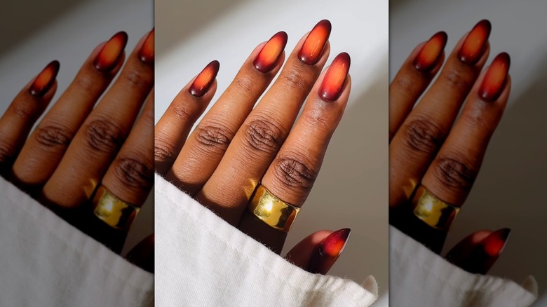 Main ouverte montrant des ongles avec un effet d'aura comportant des nuances de marron et d'orange