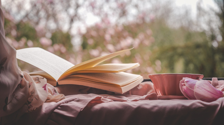 Livre avec tasse de thé et pétales de magnolia